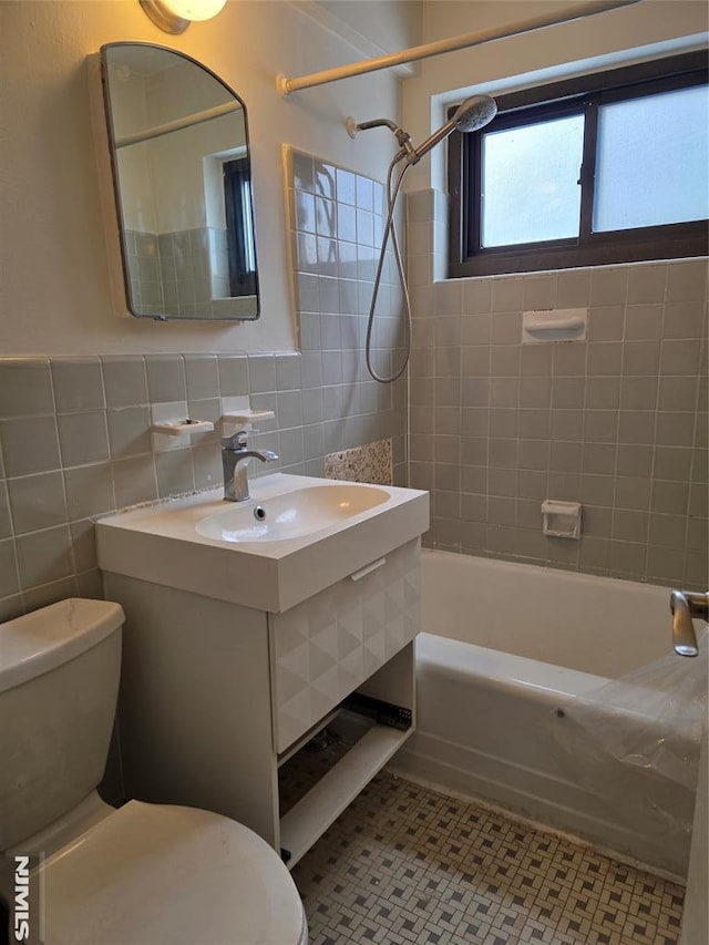 full bathroom with sink, tile walls, tile patterned floors, toilet, and tiled shower / bath