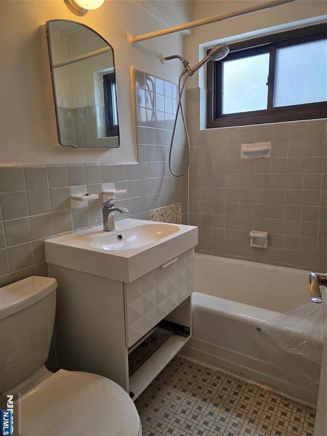 full bathroom with tile patterned floors, toilet, sink, tiled shower / bath, and tile walls