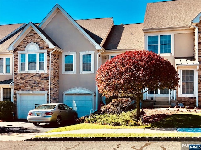 multi unit property featuring stone siding, driveway, and stucco siding