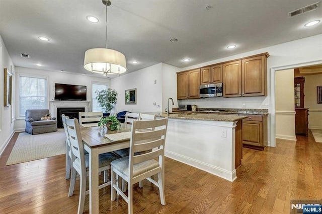 kitchen featuring light stone counters, hanging light fixtures, wood-type flooring, and sink