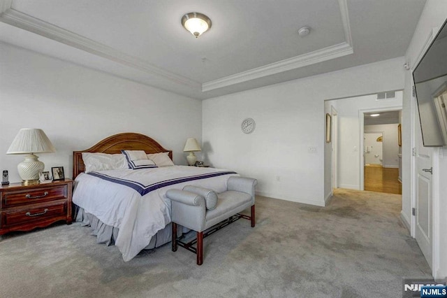 carpeted bedroom with crown molding and a tray ceiling