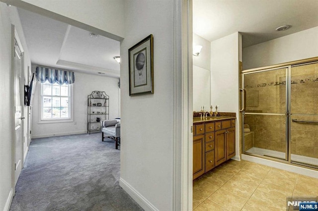 bathroom featuring tile patterned floors, vanity, a shower with shower door, and a raised ceiling