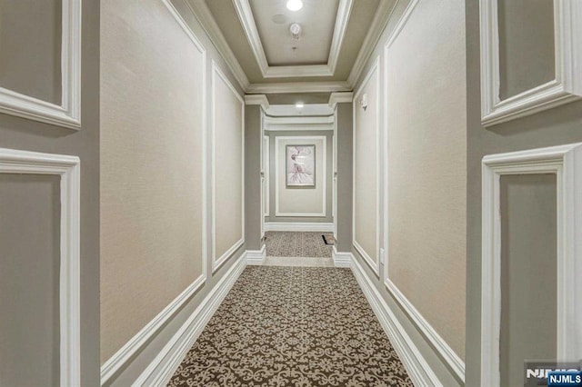 hall with crown molding and a raised ceiling