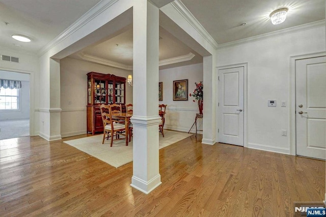 foyer featuring ornamental molding, light hardwood / wood-style floors, and ornate columns