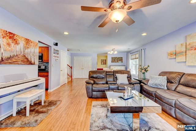 living room with ceiling fan with notable chandelier and light wood-type flooring