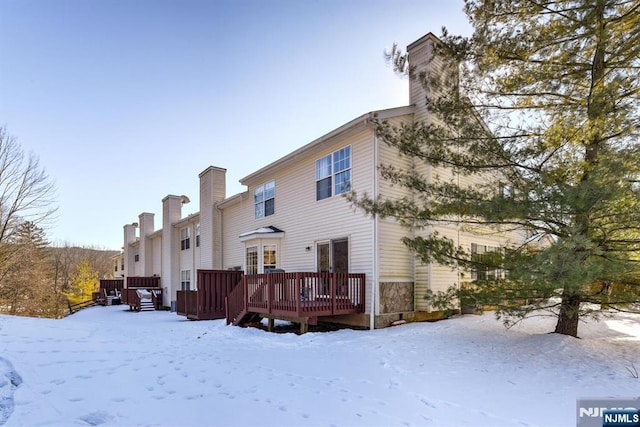 snow covered rear of property with a wooden deck