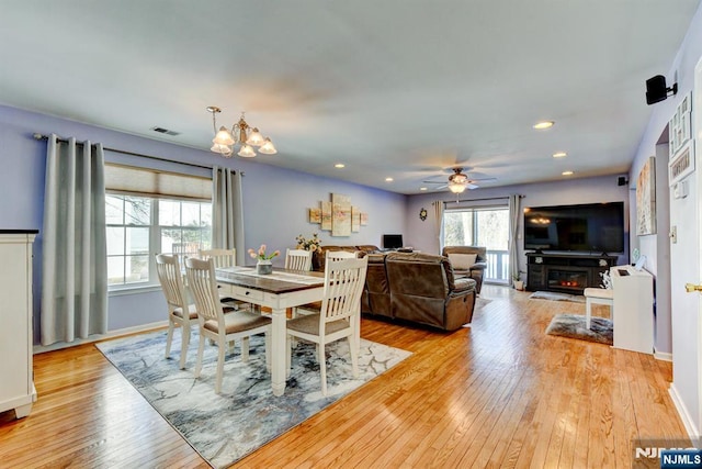 dining room featuring ceiling fan with notable chandelier and light wood-type flooring