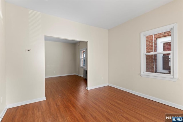 empty room with hardwood / wood-style flooring and radiator