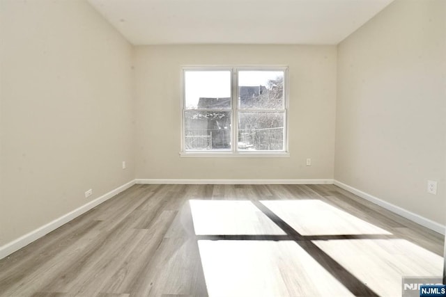 unfurnished room with baseboards and light wood finished floors