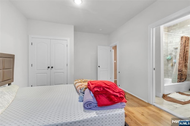 bedroom with ensuite bath, wood-type flooring, and a closet