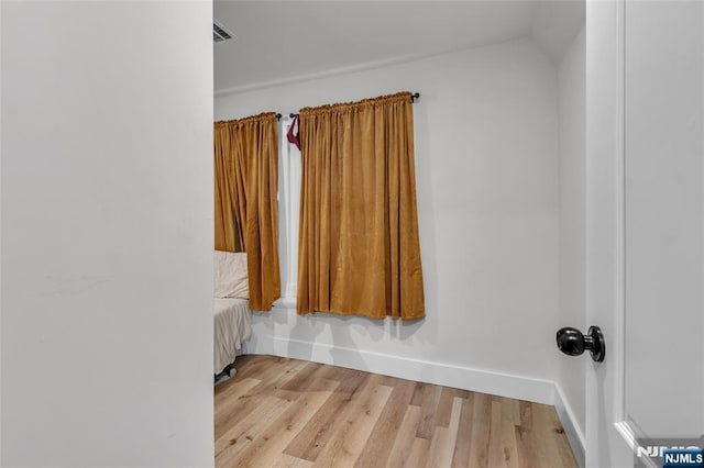 unfurnished room with lofted ceiling and light wood-type flooring