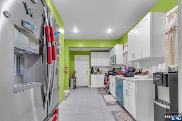 kitchen featuring tasteful backsplash, stainless steel appliances, light tile patterned floors, and white cabinets