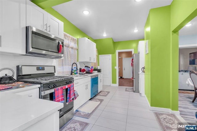 kitchen featuring backsplash, stainless steel appliances, sink, and white cabinets