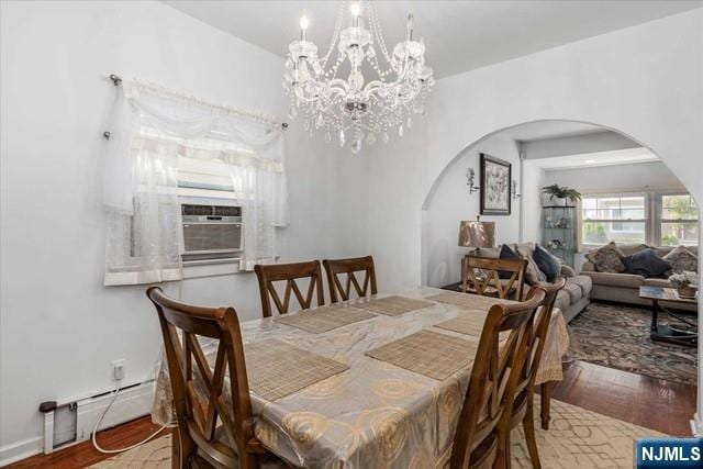 dining space with an inviting chandelier, hardwood / wood-style floors, cooling unit, and a baseboard heating unit