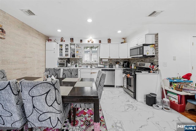 kitchen featuring tasteful backsplash, sink, white cabinets, and appliances with stainless steel finishes