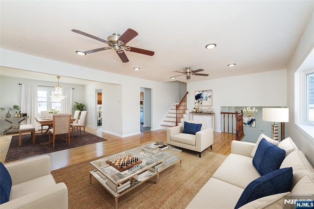 living room featuring ceiling fan with notable chandelier and light hardwood / wood-style floors