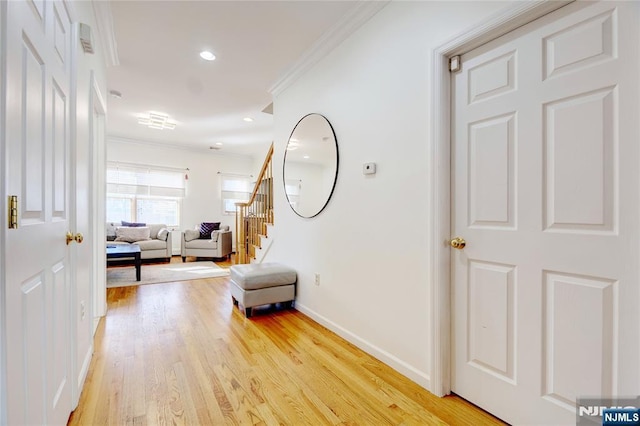 hall with ornamental molding and light wood-type flooring