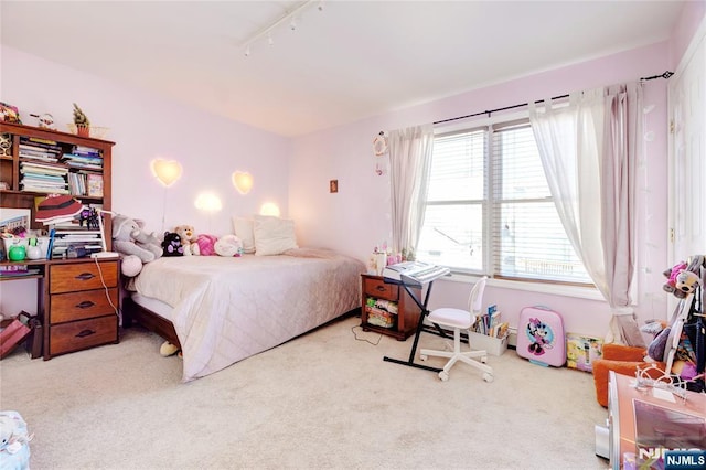 bedroom with light colored carpet and rail lighting