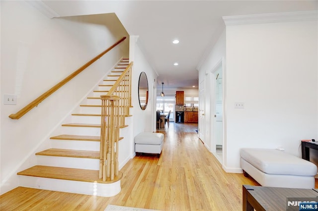 staircase with ornamental molding and hardwood / wood-style floors