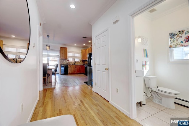 hall featuring light tile patterned floors, ornamental molding, and a baseboard heating unit