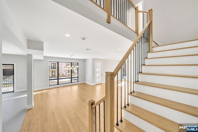 staircase with an inviting chandelier and wood-type flooring