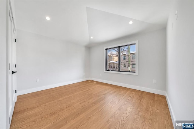 empty room with light wood-type flooring and vaulted ceiling