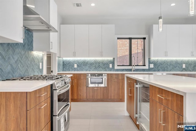 kitchen featuring white cabinetry, stainless steel appliances, decorative light fixtures, wine cooler, and wall chimney range hood