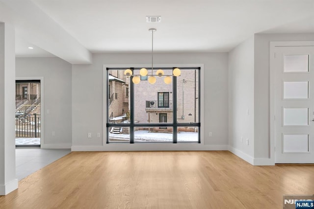 unfurnished dining area featuring light hardwood / wood-style floors and a chandelier