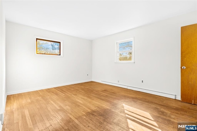 spare room with light wood-style floors, baseboards, and a baseboard radiator