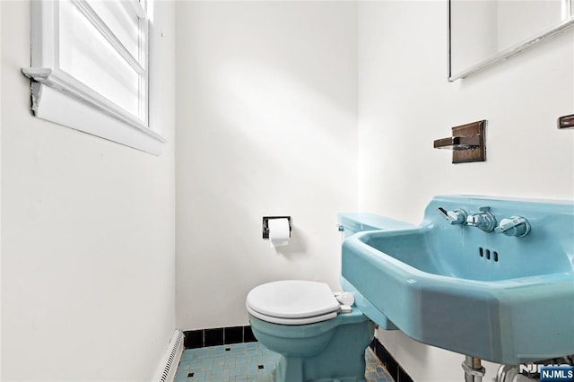 half bathroom with toilet, baseboards, and a sink