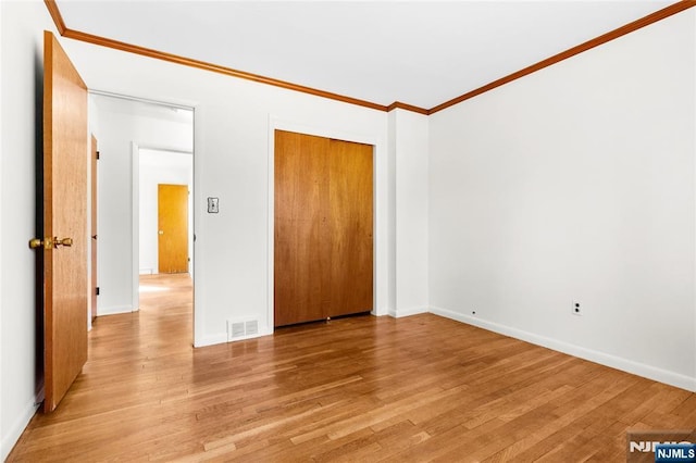 spare room with visible vents, baseboards, light wood-style floors, and ornamental molding