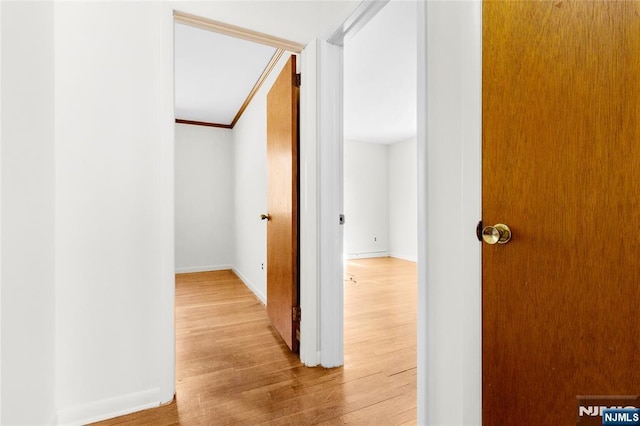 corridor featuring light wood finished floors, crown molding, and baseboards