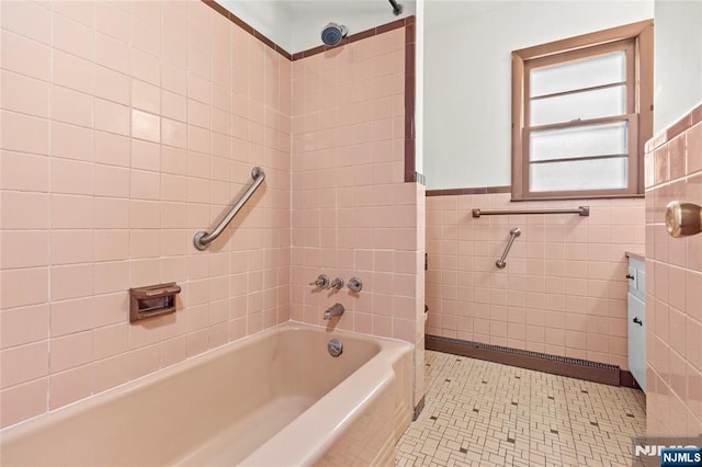 full bath with tile walls, tub / shower combination, a wainscoted wall, and tile patterned floors