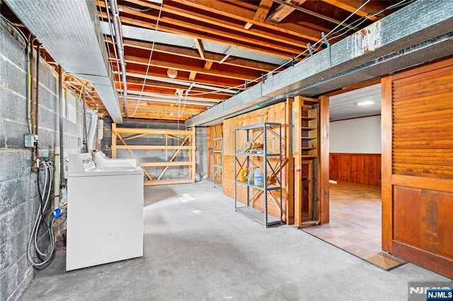 unfinished basement featuring washer and dryer, a wainscoted wall, and concrete block wall