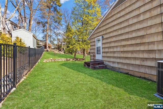 view of yard featuring central AC and fence