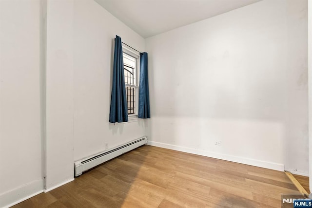 empty room featuring baseboard heating and hardwood / wood-style floors