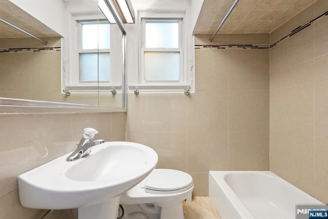 full bathroom with tile walls, sink, bathing tub / shower combination, and toilet