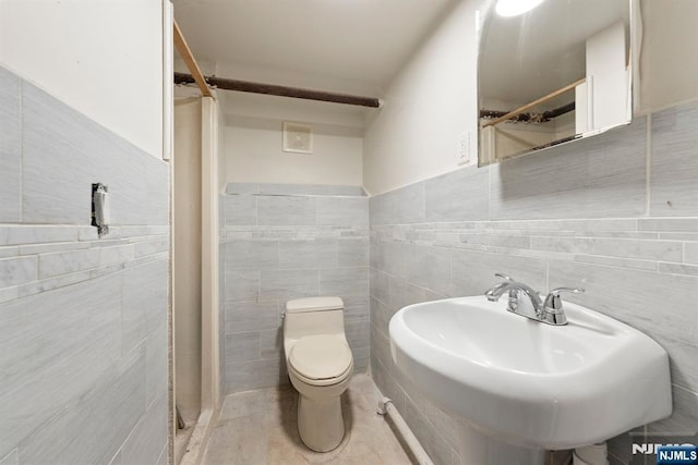 bathroom featuring sink, tile walls, and toilet