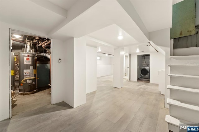 basement featuring washer / dryer, water heater, and light wood-type flooring