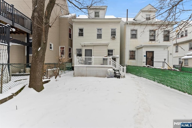 snow covered back of property with a deck