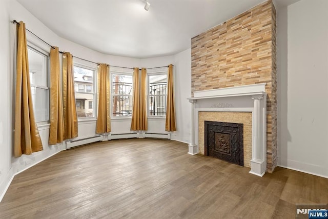 unfurnished living room featuring a tile fireplace and wood-type flooring