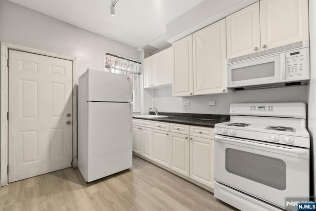 kitchen with white cabinetry, rail lighting, sink, light hardwood / wood-style floors, and white appliances