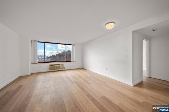 spare room with a wall mounted air conditioner and light wood-type flooring