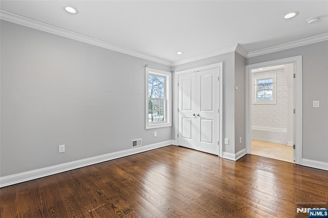 unfurnished bedroom with multiple windows, crown molding, and hardwood / wood-style flooring