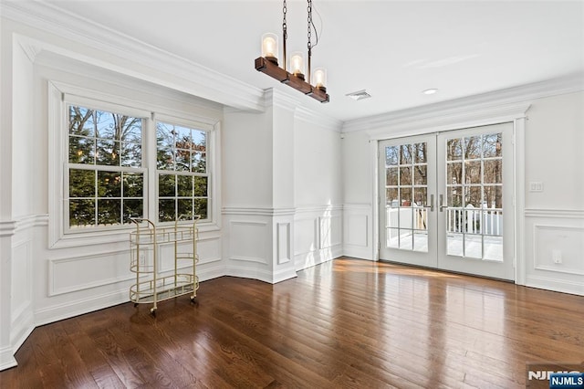 unfurnished dining area with hardwood / wood-style flooring, crown molding, a chandelier, and french doors