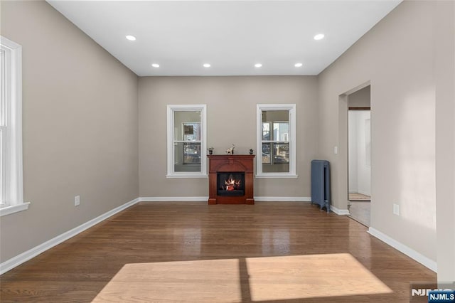 unfurnished living room featuring radiator heating unit and dark hardwood / wood-style floors