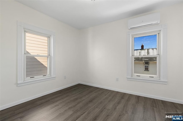 empty room featuring a wall unit AC and dark hardwood / wood-style flooring