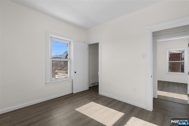 unfurnished bedroom with a closet and dark wood-type flooring