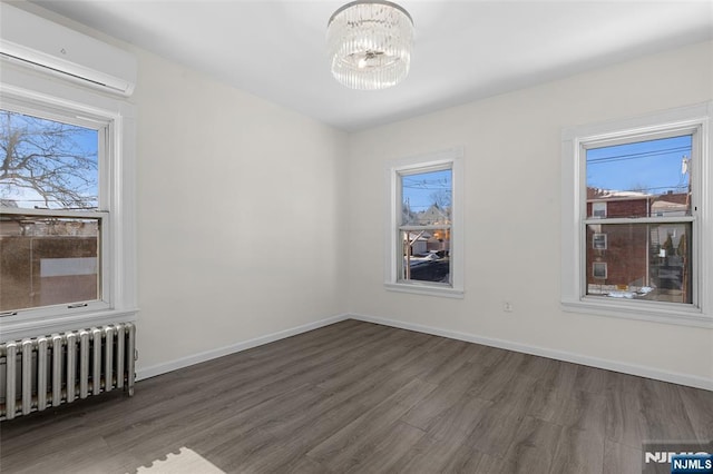 unfurnished room with radiator, dark wood-type flooring, a notable chandelier, and a wall mounted air conditioner