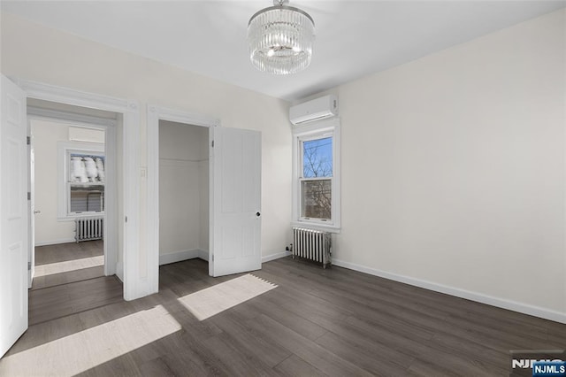 unfurnished bedroom with an inviting chandelier, a wall mounted AC, radiator, and dark hardwood / wood-style floors